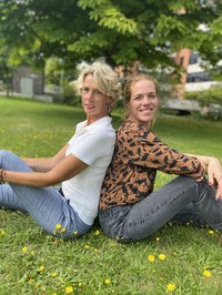 Gesine Skorsch und Nadine Helpenstein sitzen an dem Rücken der jeweils anderen angelehnt vor dem Kreishaus.