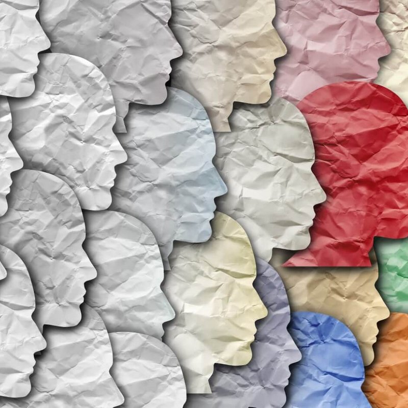 Mehrere Papierzuschnitte von einem Gesicht eines Menschen, die in verschiedenen Farben aneinandergereiht sind.