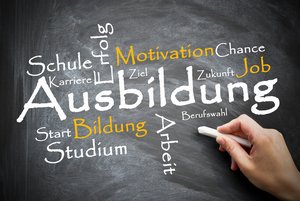 Eine Hand hält ein Stück Kreide und schreibt verschiedene Worte an einen schwarzen Hintergrund. In der Mitte des schwarzen Hintergrunds ist "Ausbildung" geschrieben. Darum herum stehen die Worte "Schule, Karriere, Erfolg, Motivation, Chance, Job, Berufswahl, Arbeit, Bildung, Studium, Start.