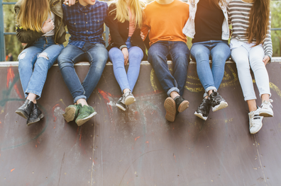 Sechs Kinder sitzen nebeneinander auf einer Skateboardrampe.